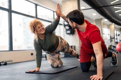 Personal Trainer gibt einer jungen Frau ein High Five nach dem Workout